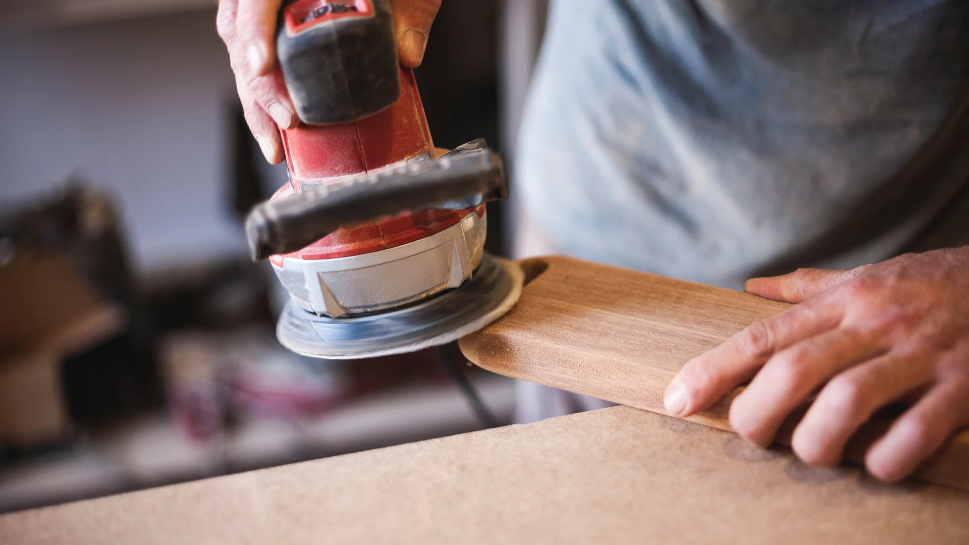 craftsmans hands using a sander